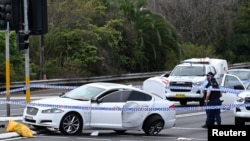 Polisi memasang tanda pembatas di sekitar mobil yang rusak akibat bertabrakan di Engadine di mana empat orang, termasuk polisi terluka akibat kecelakaan mobil dan penikaman, Minggu, 25 Agustus 2024. (Foto: Dean Lewis/AAP via Reuters)