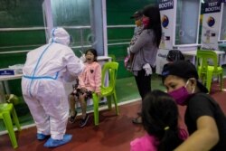 A child reacts after getting swabbed for a free coronavirus disease (COVID-19) test at a gymnasium in Navotas City, Metro Manila, Philippines, Aug. 7, 2020.
