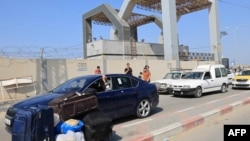 Palestinians with foreign passports arrive at the Rafah gate hoping to cross into Egypt as Israel's attacks on the Gaza Strip continues on October 14, 2023.