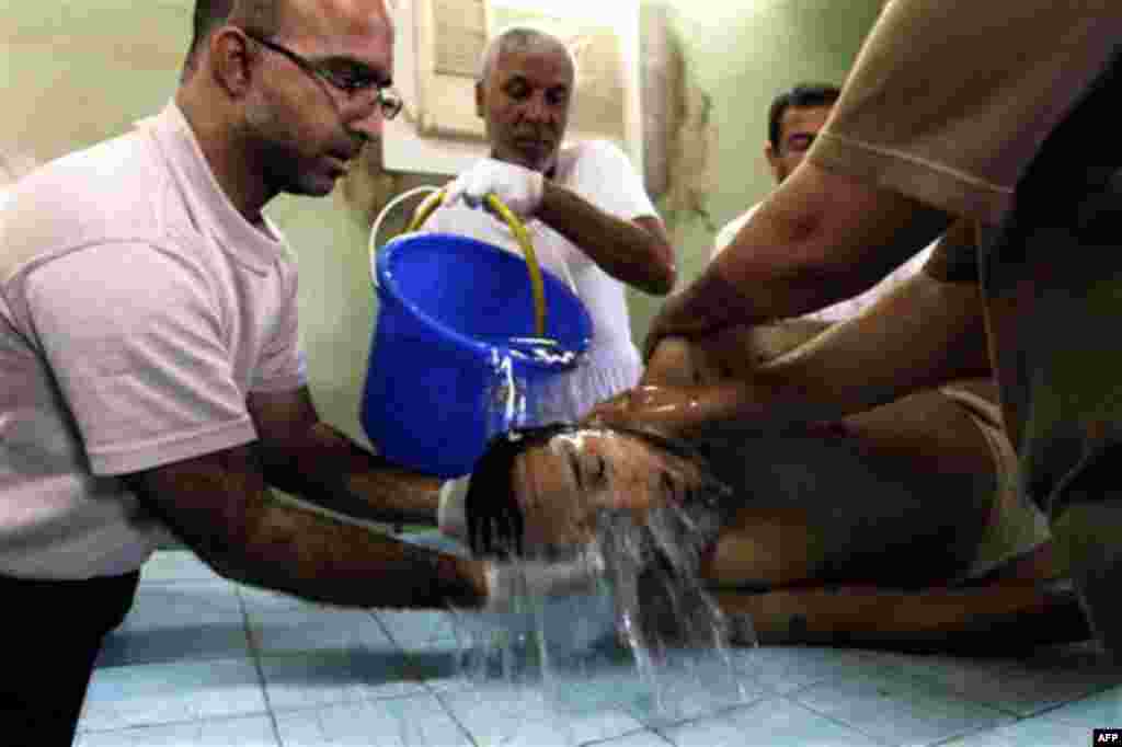 Bahraini Shiite Muslims clean the lifeless body of Mahmoud Maki Abu Taki, 22, who died during clashes between protesters and riot police on Thursday. (AP/Hassan Ammar)