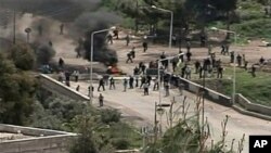 In this image made from television, protesters are seen near a barricade in Daraa, Syria, April 8, 2011