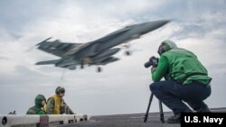 Mass Communication Specialist 2nd Class Sean Castellano, from Colorado Springs, Colo., records video footage on the flight deck of the Nimitz-class aircraft carrier USS Carl Vinson in the western Pacific region, May 23, 2017.