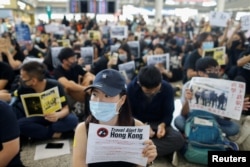 Anti-extradition bill protesters hold up placards for arriving travelers during a protest at the Hong Kong International Airport in Hong Kong, Aug. 9, 2019.