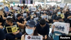 Anti-extradition bill protesters hold up placards for arriving travelers during a protest at the Hong Kong International Airport in Hong Kong, Aug. 9, 2019. 