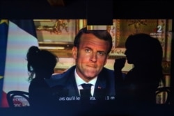 FILE - A family watches French President Emmanuel Macron's televised speech, April 13, 2020, in Lyon, central France. Macron announced an extension of France's nationwide lockdown until May 11.