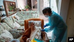 FILE - Nurse Pilar Rodríguez administers the COVID-19 vaccine to her patient, Antonia Crespi Gomila, 93, at her home in Sa Pobla, Mallorca, Spain, April 30, 2021.