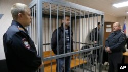 A police officers guards a cage with Greenpeace activist Ruslan Yakushev of Ukraine in a courtroom in Murmansk, Russia, Sept. 26, 2013. 