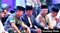 Presiden Joko Widodo (tengah) didampingi Panglima TNI Marsekal Hadi Tjahjanto (kiri) dan Kapolri Jenderal Tito Karnavian (kanan) dalam acara buka puasa bersama di di Lapangan Monumen Nasional, Jakarta, Kamis, 16 Mei 2019. 