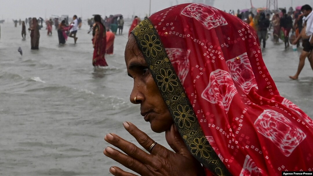 A Hindu pilgrim in India prays as she takes a holy dip at the confluence of Ganges and the Bay of Bengal during the Gangasagar Mela on the occasion of Makar Sankranti, Jan. 14, 2022. 