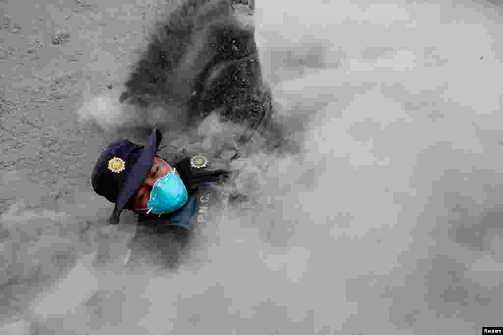 A police officer slips while running away from a new flow of ash and gas from the Fuego volcano in the community of San Miguel Los Lotes in Escuintla, Guatemala.