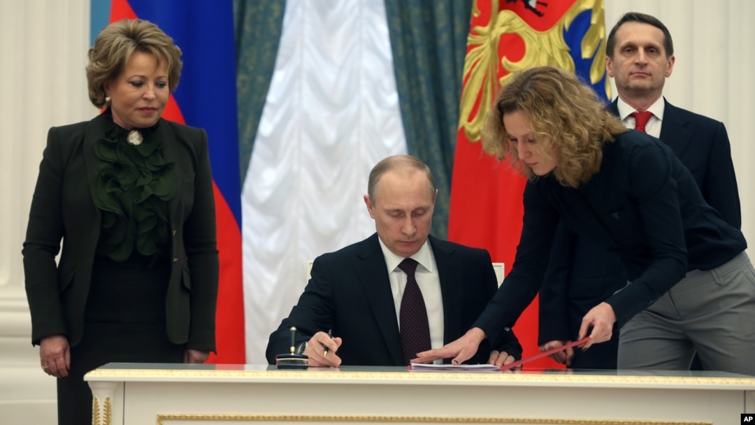 FILE - Russian President Vladimir Putin signs bills formalizing Russia's annexation of Ukraine's Crimean peninsula, in the Kremlin in Moscow, March 21, 2014.