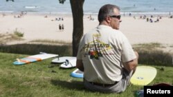 ຜູ້ຄົນລໍຖ້າເບິ່ງ ການສະແດງໂຕ້ຄື້ນ ຫລື Surfing ນໍ້າຈືດ ໃນ ເມືອງ Sheboygan, ລັດ Wisconsin, ເມື່ອວັນທີ 1 ກັນຍາ 2012, ເນື່ອງໃນວັນສຸດສັບປະດາຍາວ ຫລື long weekend ເພື່ອສະຫລອງວັນແຮງງານຢູ່ໃນສະຫະລັດ .