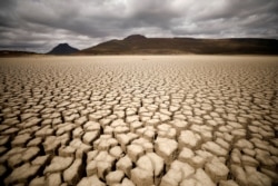 FILE - Clouds gather but produce no rain as cracks are seen in the dried up municipal dam in drought-stricken Graaff-Reinet, South Africa, Nov. 14, 2019.