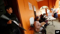 Un policier patrouille dans un bureau de vote de Oaxaca, 7 juillet 2013.