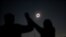 People react while observing a solar eclipse at Incahuasi, a mountain in Chile, July 2, 2019. 