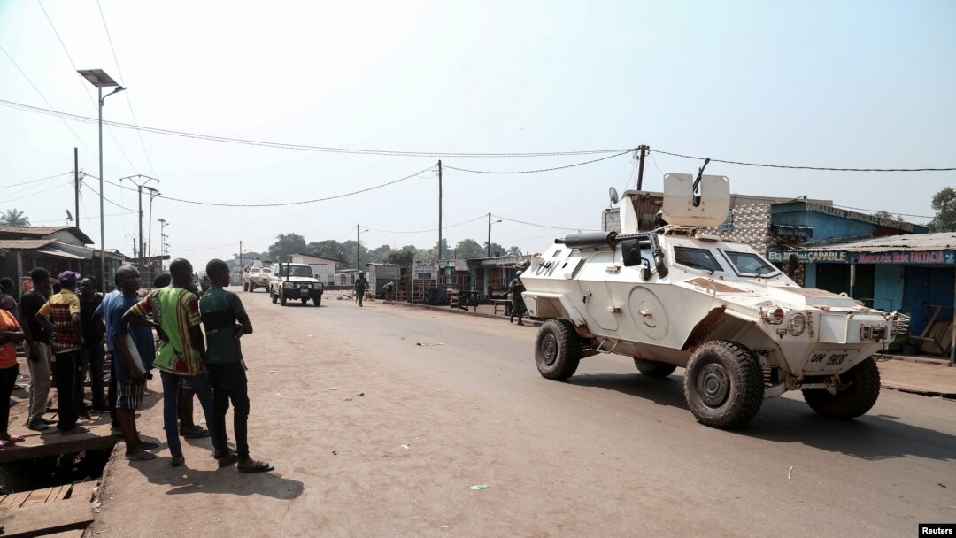 Residents watch as a U.N. Multidimensional Integrated Stabilization Mission in the Central African Republic (MINUSCA) armored personnel carrier patrols after attacks in Begoua, a northern district of Bangui, C.A.R., Jan. 13, 2021.