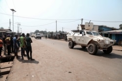 FILE - Residents watch as a U.N. Multidimensional Integrated Stabilization Mission in the Central African Republic (MINUSCA) armored personnel carrier patrols after attacks in Begoua, a northern district of Bangui, C.A.R., Jan. 13, 2021.