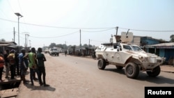 FILE - Residents watch as a U.N. Multidimensional Integrated Stabilization Mission in the Central African Republic (MINUSCA) armored personnel carrier patrols after attacks in Begoua, a northern district of Bangui, Jan. 13, 2021.