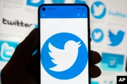 FILE - The Twitter logo is seen on a cell phone, Friday, Oct. 14, 2022, in Boston. The “official” designation for major corporate accounts on Twitter appeared, vanished, and depending on the account, appeared or vanished again and some companies took to the social media platform to warn of imposters. (AP Photo/Michael Dwyer, File)