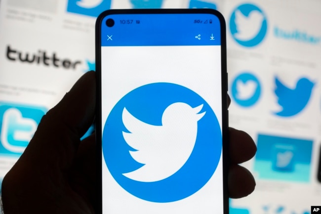 FILE - The Twitter logo is seen on a cell phone, Friday, Oct. 14, 2022, in Boston. The “official” designation for major corporate accounts on Twitter appeared, vanished, and depending on the account, appeared or vanished again and some companies took to the social media platform to warn of imposters. (AP Photo/Michael Dwyer, File)