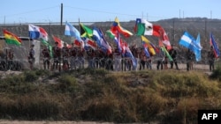 Activistas estadounidenses ondean banderas durante una misa binacional para recordar a los migrantes que han muerto intentando llegar a los EE.UU. en las orillas del Río Bravo/Grande en la frontera de El Paso, Texas, el 9 de noviembre de 2024. AFP