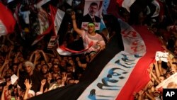Supporters of Egypt's ousted President Mohammed Morsi hold a large Egyptian national flag as they chant slogans against Defense Minister Gen. Abdel-Fattah el-Sissi, in Cairo, Aug. 2, 2013. 