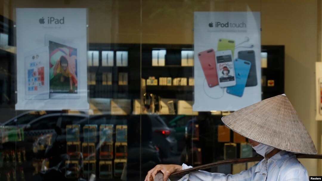 Penjual buah berjalan melewati toko Apple di Hanoi (24 April 2014). Negara komunis Vietnam tiba-tiba menjadi pasar terhangat Apple setelah penjualan produk Apple meningkat tiga kali lipat dalam tiga bulan pertama tahun ini, jumlah yang lebih tinggi lima kali lipat daripada di India.