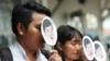 Demonstrators hold masks of Thai pro-democracy activist Sirawith Seritiwat during a protest at police headquarter in Bangkok, Thailand, July 3, 2019.