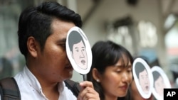 Demonstrators hold masks of Thai pro-democracy activist Sirawith Seritiwat during a protest at police headquarter in Bangkok, Thailand, July 3, 2019.