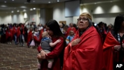 Confederated Tribes of Siletz Indians member Ramona Hudson looks up as her cousin Aurora Chulik-Ruff, 12, holds her 5-month-old brother, Bear Chulik-Moore, as they walk during a dance dedicated to missing and murdered Indigenous women on Nov. 16, 2024, in Lincoln City, Ore. 