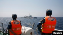 Officers of the Vietnamese Marine Guard monitor a Chinese coast guard vessel (top) on the South China Sea, about 210 km (130 miles) offshore of Vietnam, May 15, 2014.