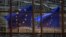 FILE - A European Union flag is reflected in a building of the EU headquarters in Brussels. 