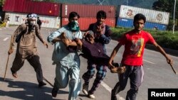 Pendukung Tahir ul-Qadri, ulama Sufi dan pemimpin partai politik Pakistan Awami Tehreek (PAT), membawa seorang demonstran yang cedera dalam Revolution March di Islamabad 31 Agustus 2014.