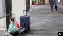 FILE - Katelyn Darrow gets some work done on her laptop as she waits to board her flight at the Philadelphia International Airport, Dec. 31, 2021, in Philadelphia. 