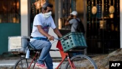 Un hombre con un tapabocas monta su bicicleta por una calle de La Habana, el pasado 29 de julio.