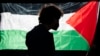 La silueta de un alumno de la Universidad de Oregon se ve ante una bandera palestina en un campamento de carpas levantado en la universidad como protesta por la guerra entre Hamás e Israel, el 29 de abril de 2024 en Eugene, Oregon. 