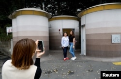 Tourists get their photos taken in front of a public toilet during a Tokyo Toilet Shuttle Tour, at Shibuya ward, in Tokyo, Japan April 4, 2024. (REUTERS/Kim Kyung-Hoon)