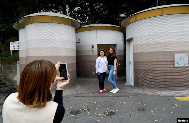 Tourists get their photos taken in front of a public toilet during a Tokyo Toilet Shuttle Tour, at Shibuya ward, in Tokyo, Japan April 4, 2024. (REUTERS/Kim Kyung-Hoon)