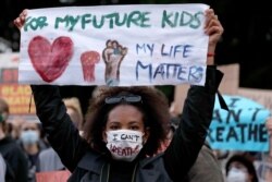 A woman holds a sign as protesters gather in Sydney, June 2, 2020, to support the cause of U.S. protests over the death of George Floyd and urged their own governments to address racism and police violence.