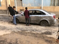 FILE - Libyan boys check a damaged car after a shell fell on a residential area at Hadba al-Badri district, in Tripoli, Libya, Jan. 28, 2020.