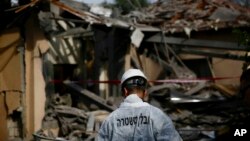 Seorang polisi Israel memeriksa sebuah rumah warga di Mishmeret, Israel Tengah yang hancur akibat serangan roket dari Gaza, Senin pagi (25/3). 