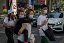 FILE - Chinese family wearing face masks walk in a pedestrian crossing in Bangkok, Thailand, Jan. 29, 2020.