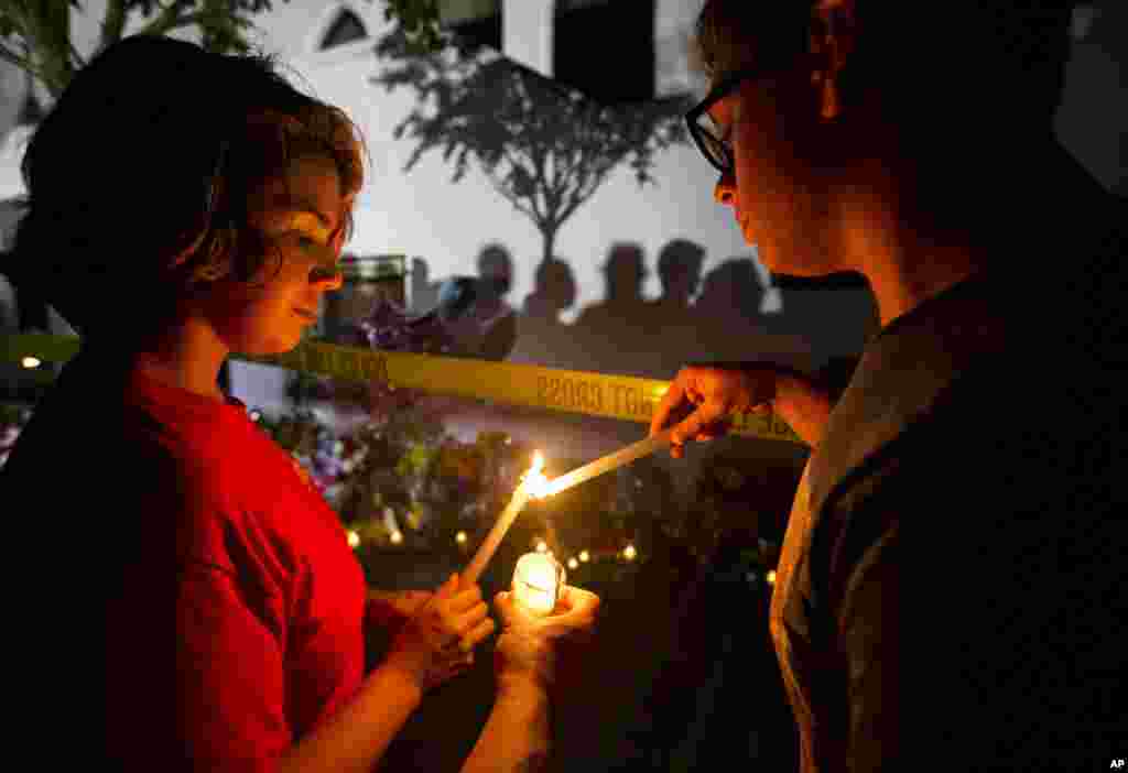 Olina Ortega, left, and Austin Gibbs light candles at a sidewalk memorial in front of Emanuel AME Church where people were killed by a white gunman Wednesday during a prayer meeting inside the historic black church in Charleston, S.C., June 18, 2015. 