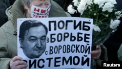 A woman holds a placard with a portrait of Sergei Magnitsky during an unauthorised rally in central Moscow December 15, 2012. 