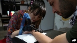 Tattoo artist Suraya Shaheedi, 26, creates a tattoo for a male customer in Kabul, Afghanistan, Nov. 9, 2019.