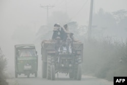 Para pekerja berkendara di jalan raya yang diselimuti kabut asap di pinggiran kota Lahore pada 6 November 2024. (Foto: AFP)