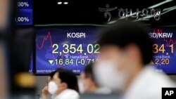 Currency traders work near the screens showing the Korea Composite Stock Price Index, left, and the foreign exchange rate between US dollar and South Korean won in Seoul, South Korea, Oct. 22, 2020.