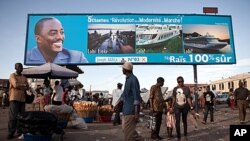 People walk under a giant poster showing Democratic Republic of the Congo 's President and candidate for a second term Joseph Kabila, in Kinshasa, November 7, 2011.