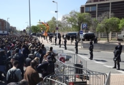 FILE - Catalan police stand guard in front of demonstrators during a protest outside a building where Spain's King Felipe was attending a ceremony in Barcelona, Spain, Apr. 9, 2018.