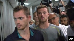 Dua perenang Olimpiade AS, Gunnar Bentz (kiri) dan Jack Conger meninggalkan kantor polisi di bandara Rio de Janeiro, Rabu (17/8).